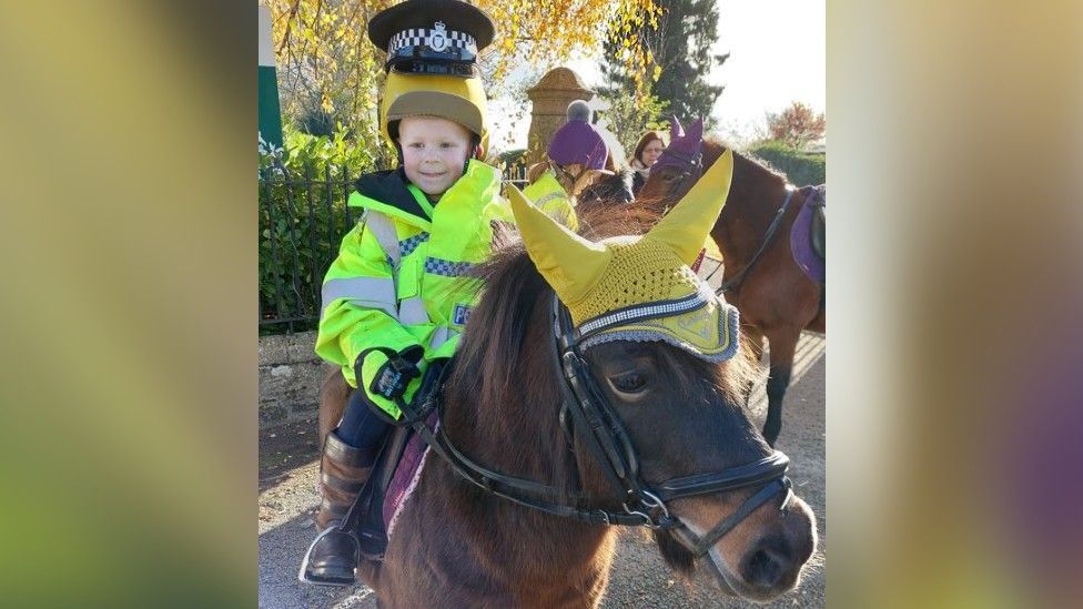 Kodie in police uniform riding Coco the pony