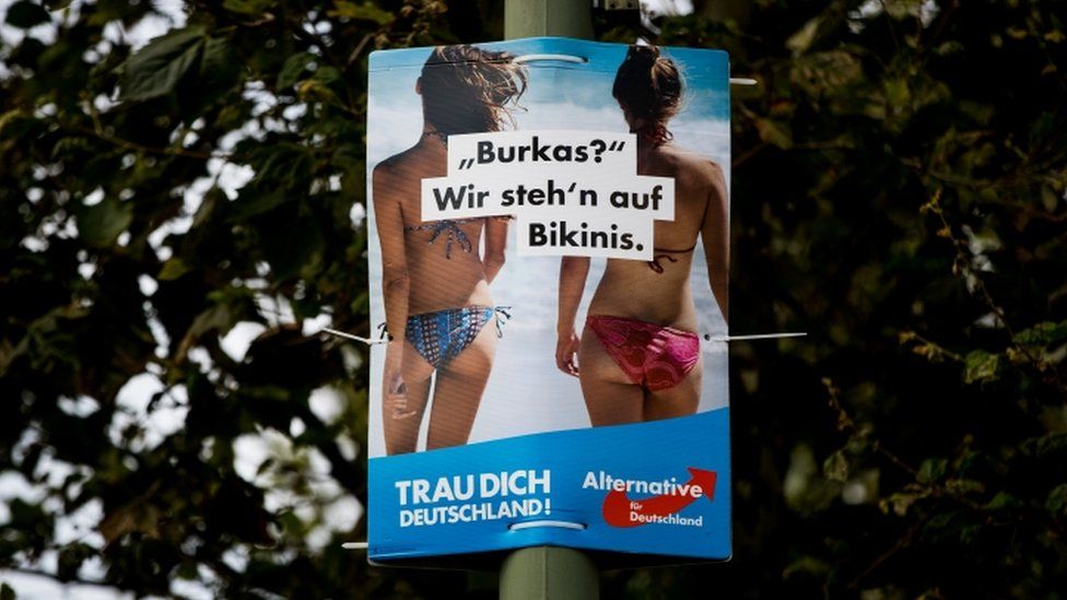Political poster with "Burkas? We like bikinis" slogan tied to a post