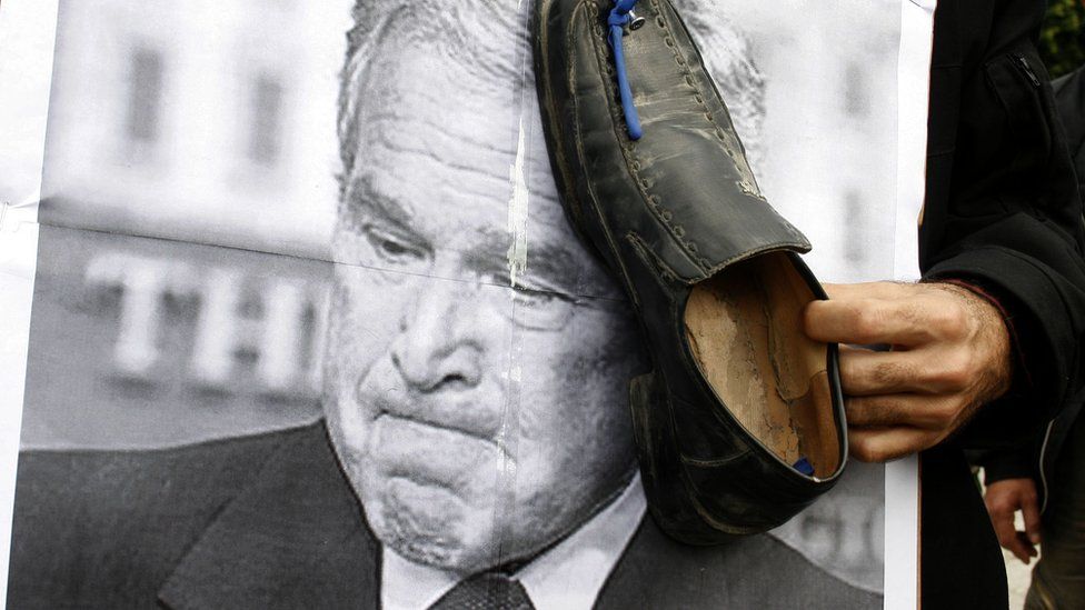 A Palestinian man holds a shoe on a poster of US President George W Bush during a demonstration in support of Muntadar al-Zaidi on 16 December 2008 in Gaza City