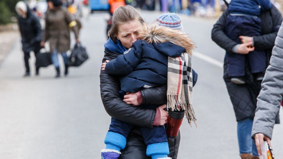 Woman crossing the border between Ukraine and Slovakia carrying a child