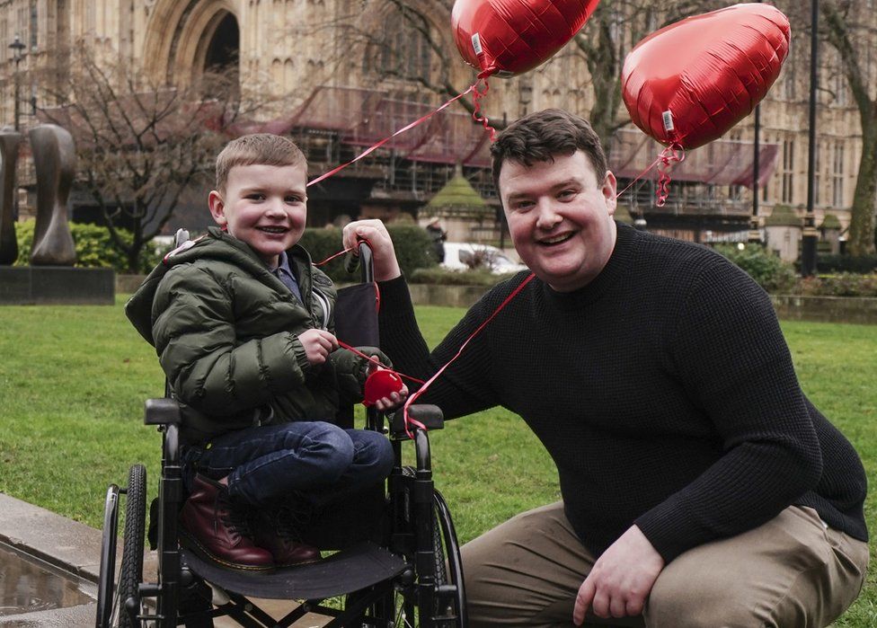 Máirtín and Dáithí Mac Gabhann in London hold red heart-shaped balloons