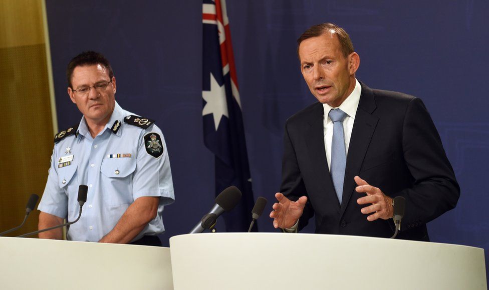 Australia's Prime Minister Tony Abbott (R) speaks to the media as Australian Federal Police deputy commissioner Michael Phelan (L) listens in Sydney on 18 April 2015, after two men were arrested in Melbourne for allegedly planning an Islamic State-inspired terrorist attack using 'edged knives' on a ceremony commemorating Anzac soldiers who have fought and died for their country