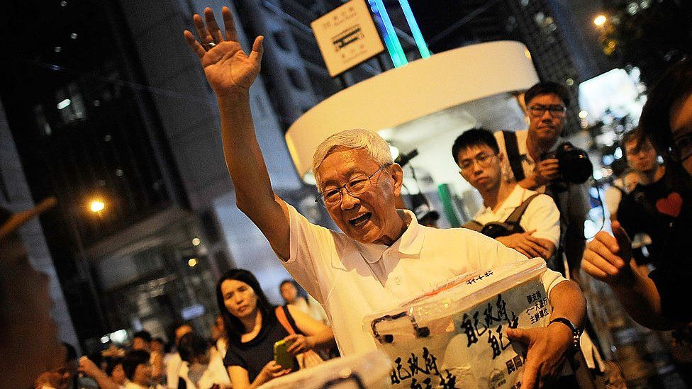 Кардинал в отставке Джозеф Зен Зе-киун машет рукой протестующим во время ежегодного протеста в поддержку демократии 1 июля 2014 года в Гонконге