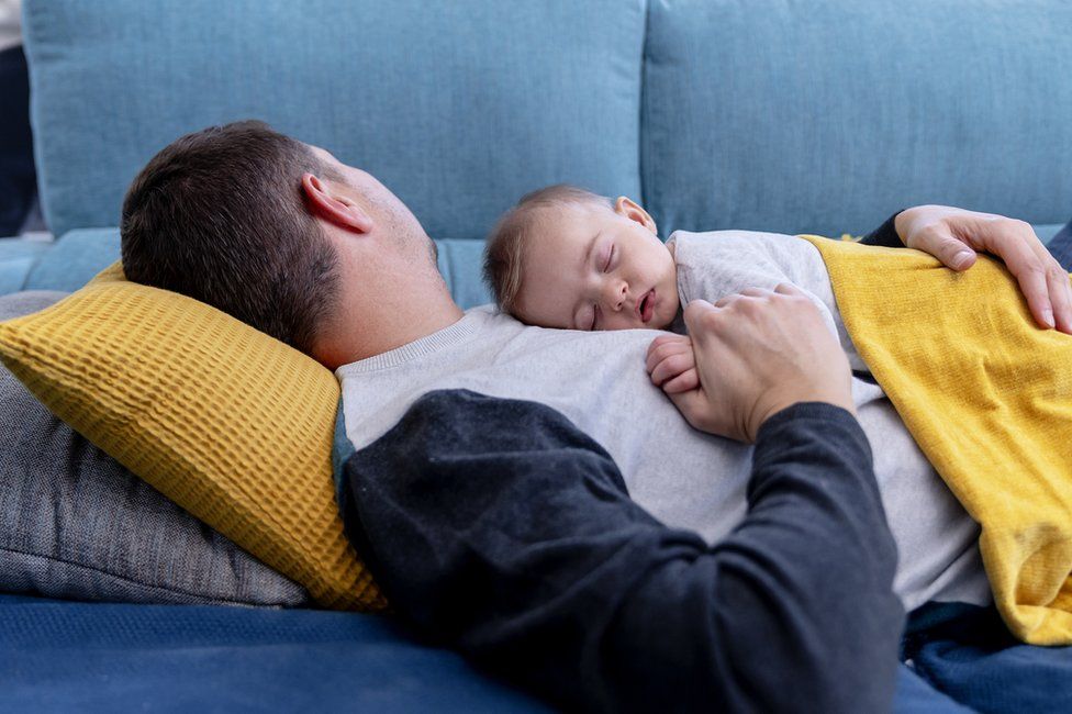 Man sleeping on sofa with child