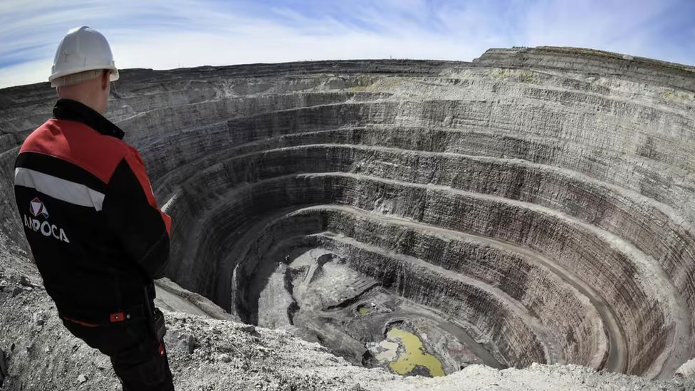 A worker stands over an openpit mine