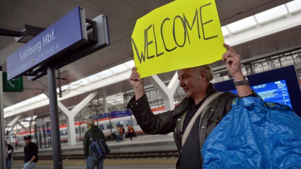 A traveller holds up a sign greeting refugees in transit at Salzburg railway station, 5 September