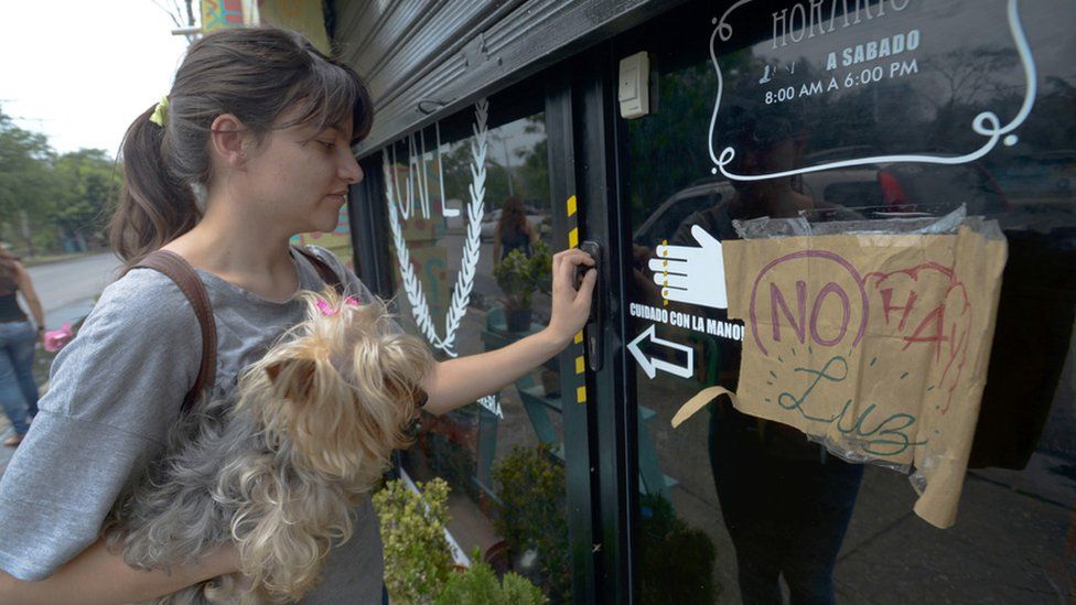 A young woman tries to enter a cafe, closed due to a power cut, in Maracay, Venezuela, on April 25, 201