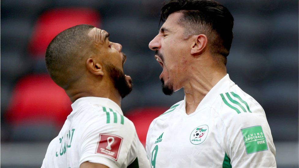 Two football players celebrating. They are close to one another and appear to be shouting or cheering.