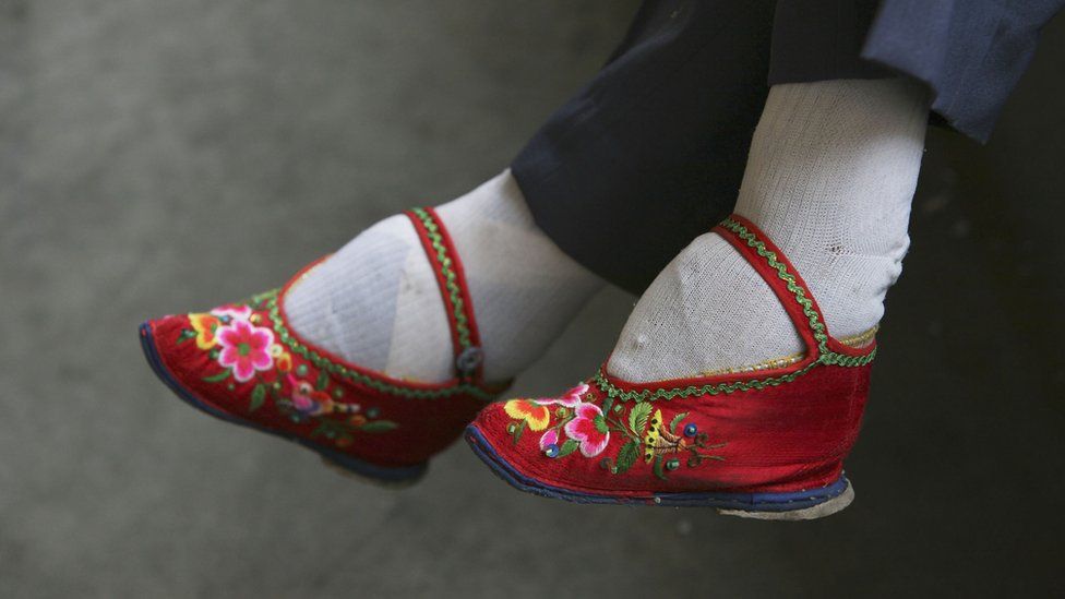 A member of the Bound Feet Women Dancing Team, wearing her 'Three Cuns Golden Lotus' shoes, prepares for dancing practice at Liuyi Village on April 2, 2007 in Tonghai County of Yunnan Province, China.