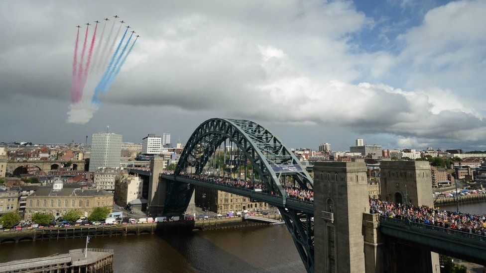 The Red Arrows display team soar over the Tyne Bridge as thousands of runners cross it