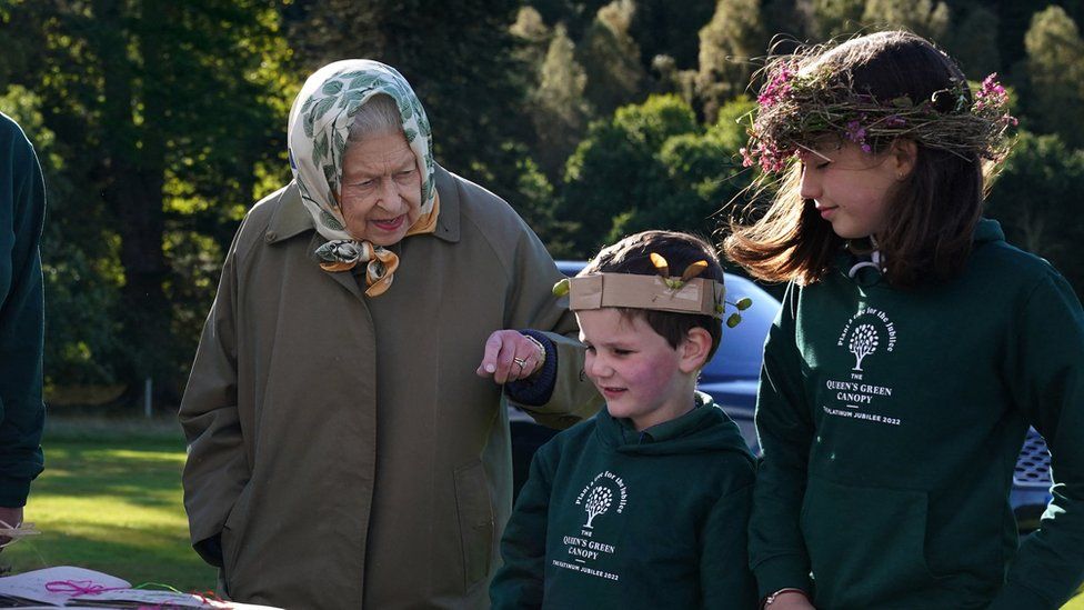 Britain's Queen Elizabeth II interacts with school children from Crathie Primary before planting a tree at Balmoral Cricket Pavilion with Britain's Prince Charles, Prince of Wales, to mark the start of the official planting season for the Queen's Green Canopy (QGC), on the Balmoral Estate in Scotland on October 1, 2021.