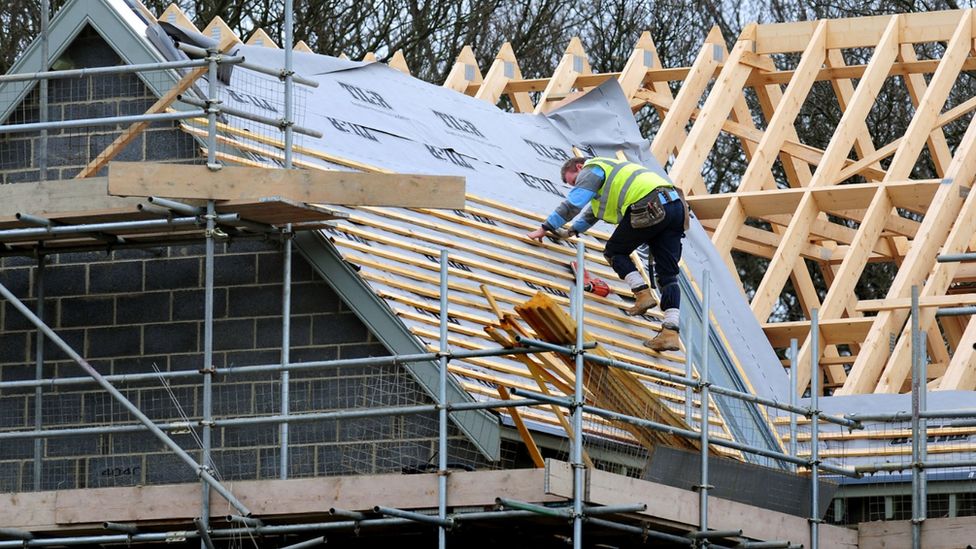 Builder works on the construction of the roof of a house