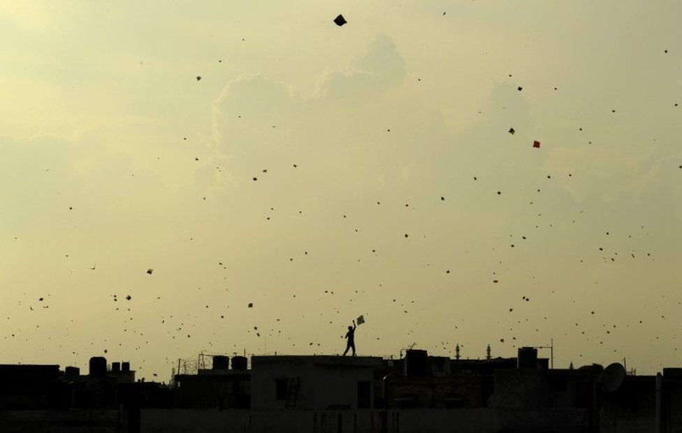 На этой фотографии из архива, сделанной 15 августа 2013 года, мальчик запускает воздушного змея с крыши дома, в то время как другие воздушные змеи, кажется, слетаются в небо над головой, когда индийцы празднуют День независимости в Нью-Дели, I
