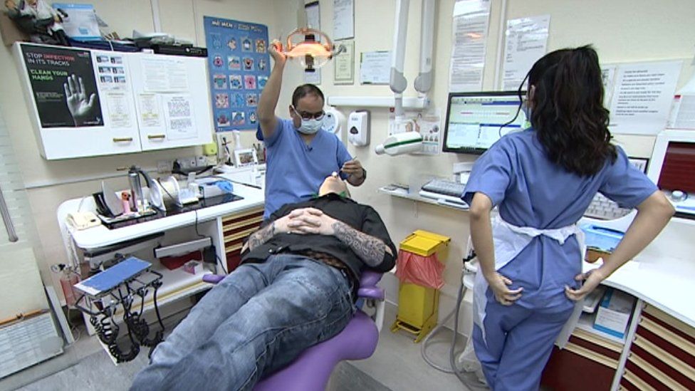 General view of a patient, dentist and dental assistant