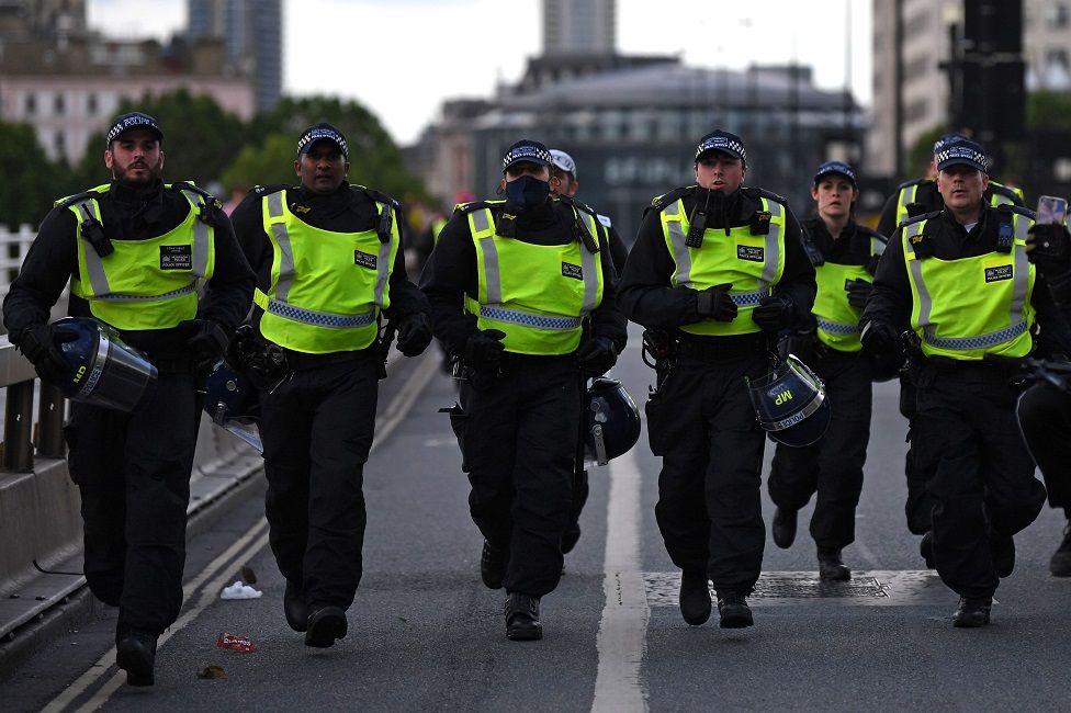 Police officers runs across Waterloo Bridge to reinforce colleagues on the Strand after protesters supporting the Black Lives Matter movement clash with opponents in central London
