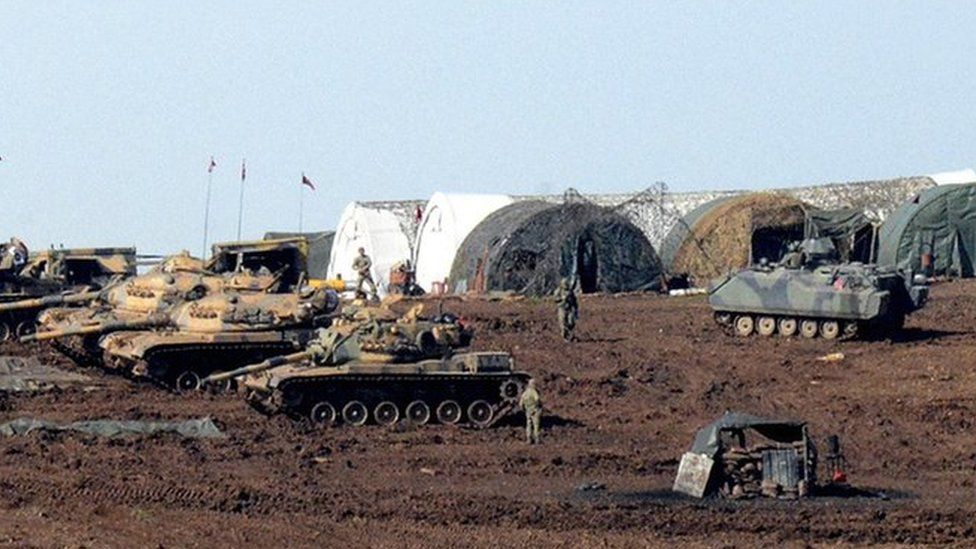 Turkish Army vehicles and tanks wait near the Syrian border in Suruc on February 23, 2015