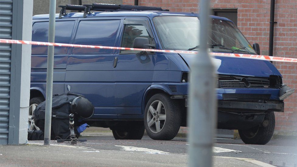 A bomb disposal expert examines the prison officer's van after the explosion in Hillsborough Drive, east Belfast