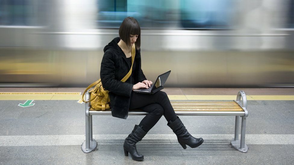 woman using laptop at train station