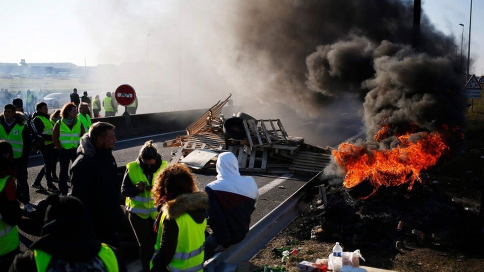 French protesters stand near a fire and blockade in western France