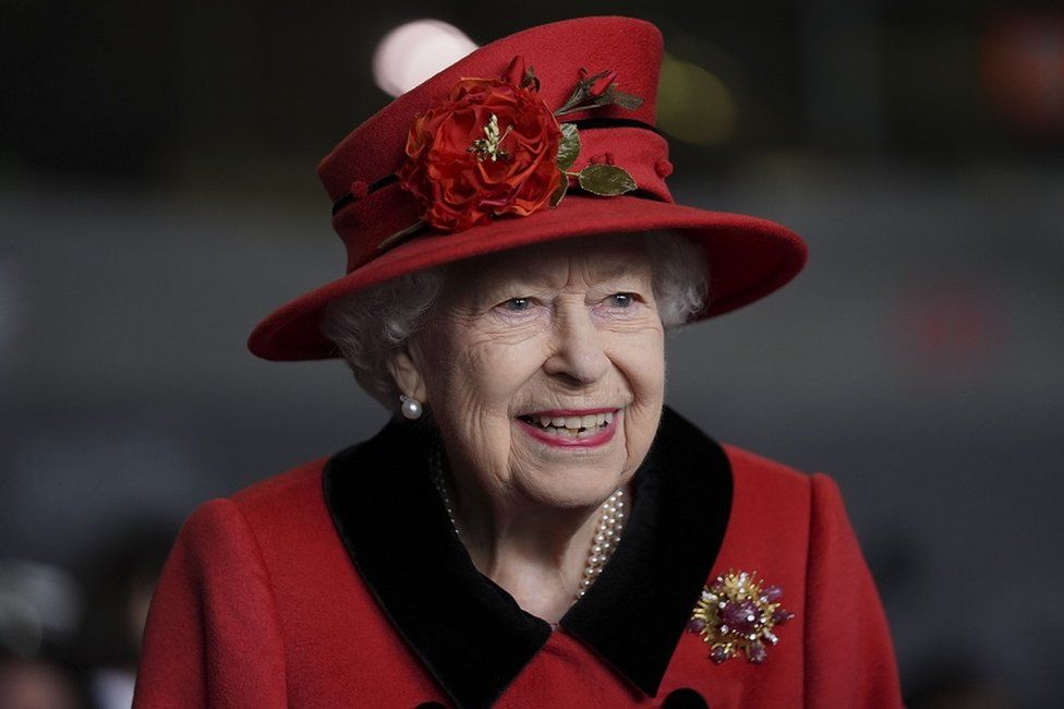 The Queen in a red hat and coat
