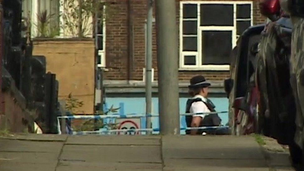 Policewoman stands outside house