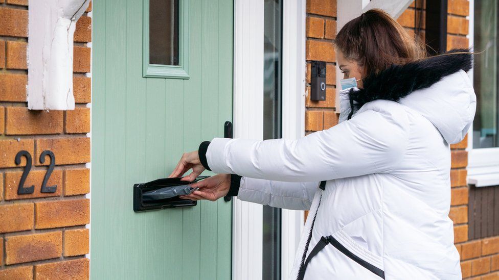 Volunteer Hanna Taylor delivers coronavirus test kits during door-to-door coronavirus testing in Woking, Surrey