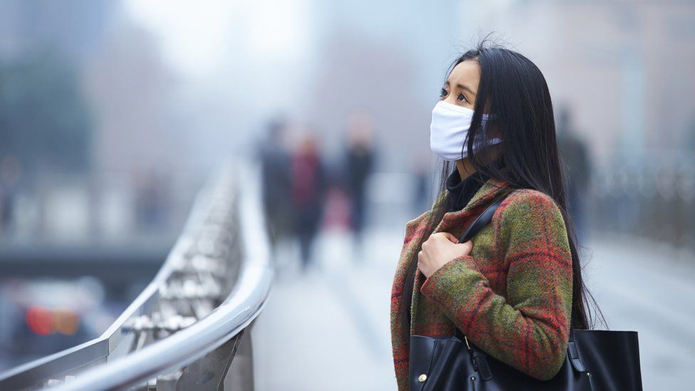 Woman wearing face mask in polluted city