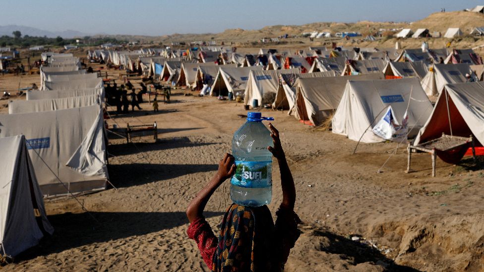Girl carries water bottle into camp for people displaced by Pakistan flooding
