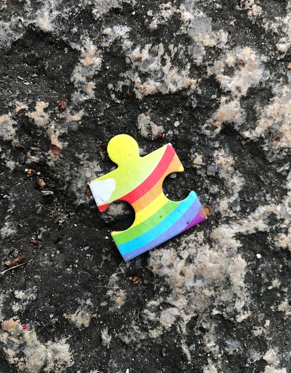 Rainbow coloured jigsaw piece on the ground