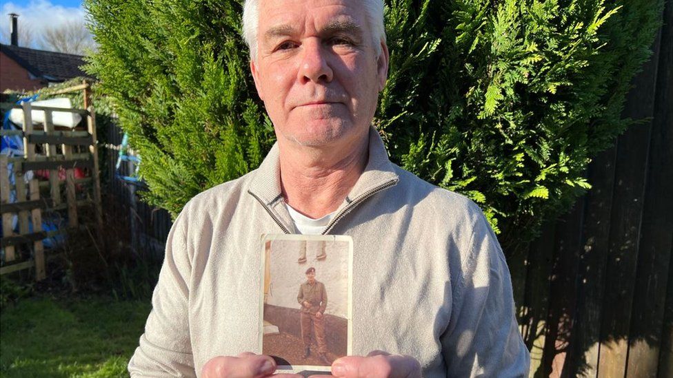 Terry Cadwallander holds a picture of his brother Geoffrey