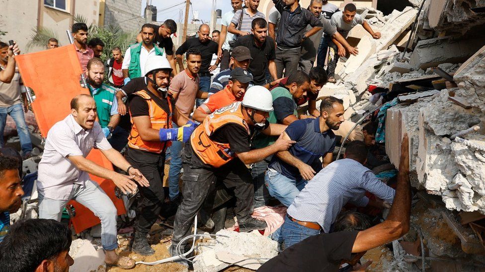 Palestinians search for casualties under the rubble of a house destroyed in an Israeli strike in Khan Younis, in the southern Gaza Strip (8 October 2023)