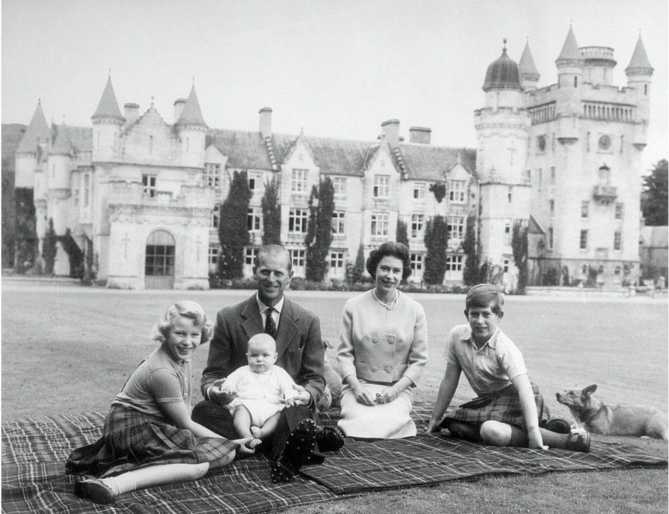 Baby Prince Andrew perches on Prince Philip's lap during a picnic in the grounds of Balmoral Castle. Also pictured are Queen Elizabeth, Prince Charles, and Princess Anne.