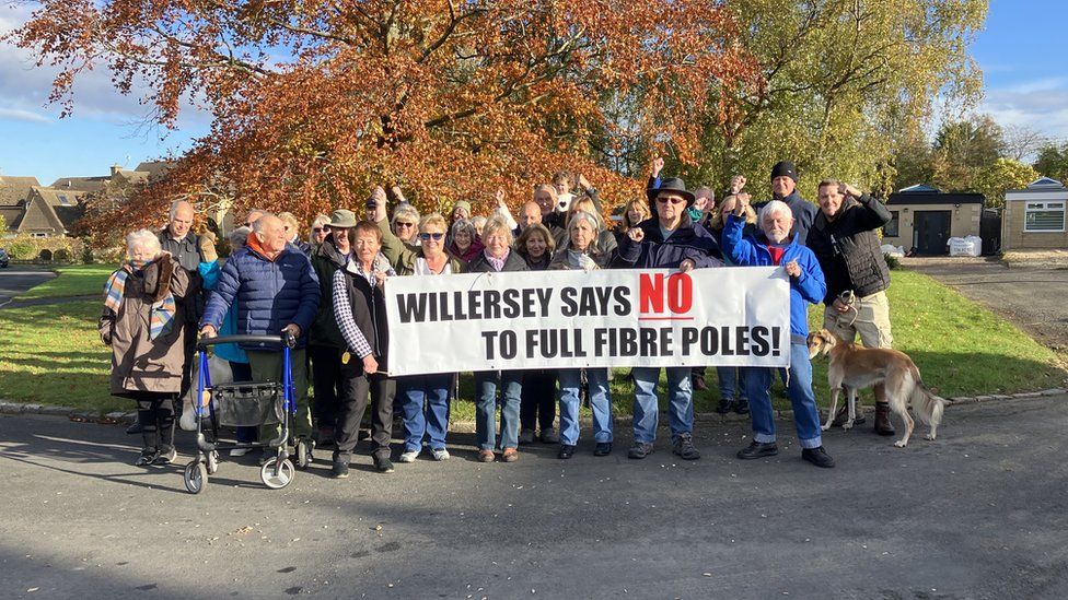 A group of people holding a banner saying Willersey Says No To Full Fibre Poles