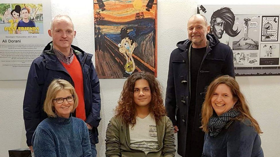 Photo showing Ali Dorani at an exhibition of his work in Norway, surrounded by visitors to the gallery