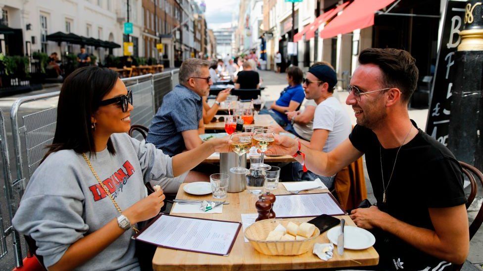 Diners enjoy their drinks as they sit at tables outside a restaurant in London on 3 August, 2020