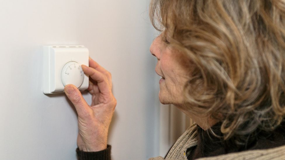 Woman adjusts thermostat