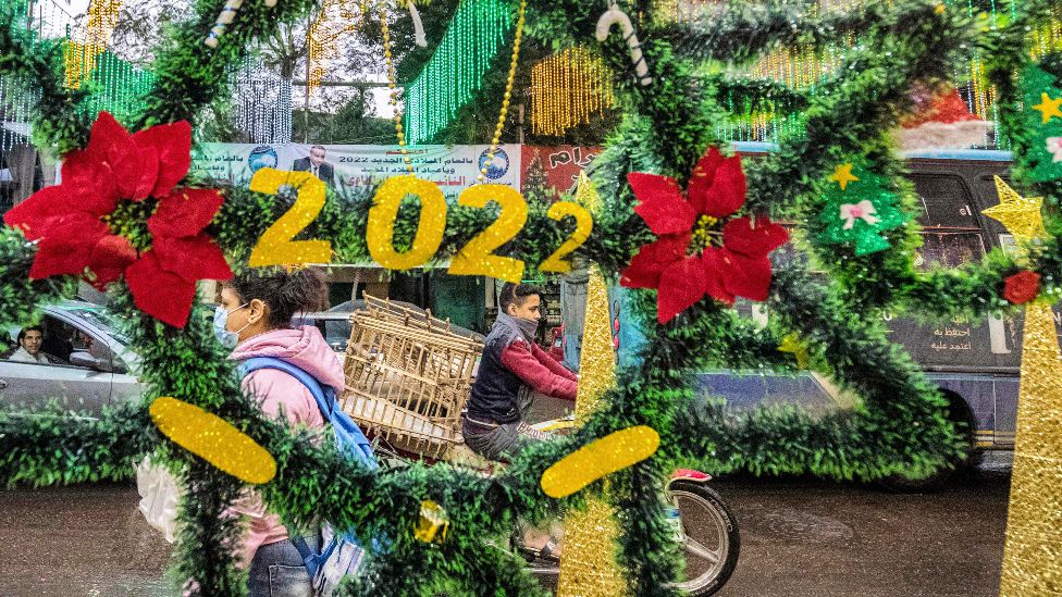 People pass Christmas decorations reading "2022" on display at a shop in Cairo, Egypt - Friday 31 December 2021