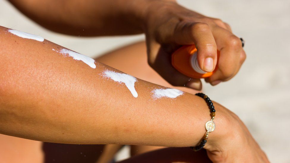 Woman putting suncream on arms