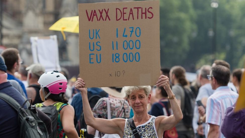 Woman holds a sign claiming vaccines are causing deaths