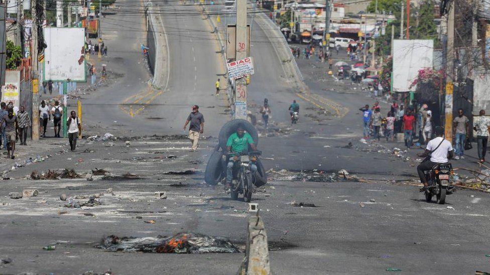 People walk on an empty street with remains of barricades during a nationwide strike against rising fuel prices, in Port-au-Prince, Haiti September 26, 2022.
