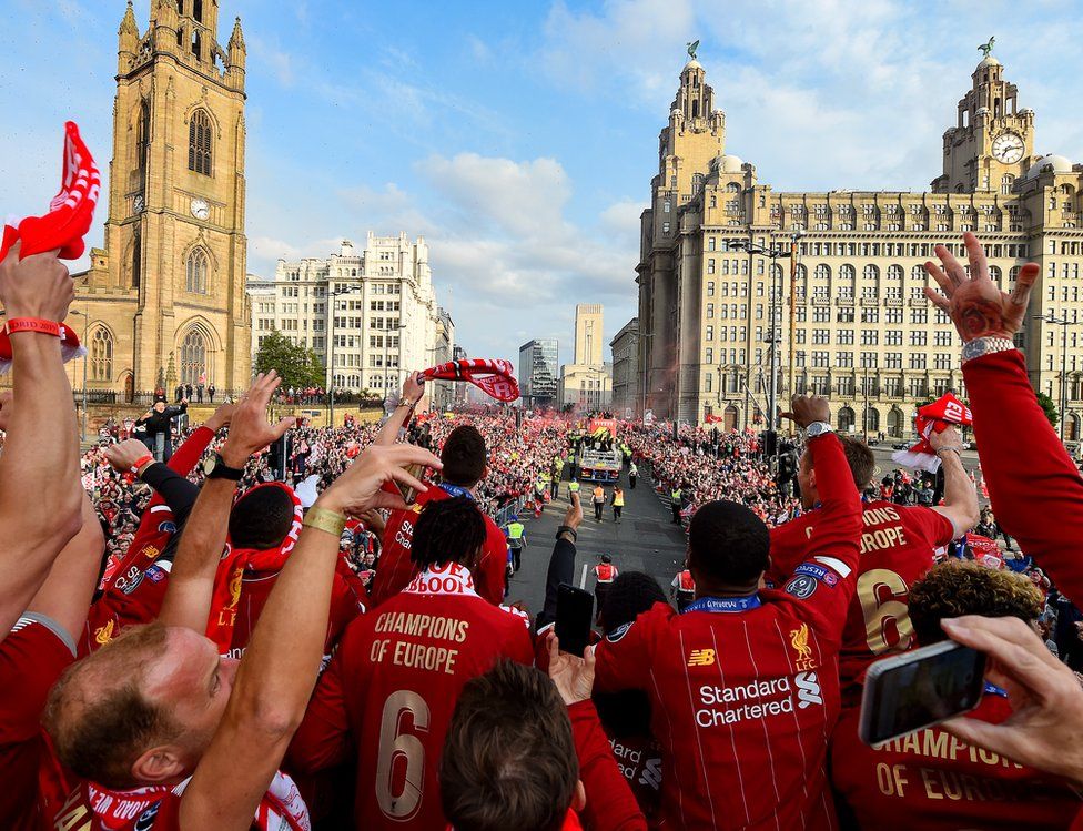 Liverpool players celebrating as they go near the Liver Birds building