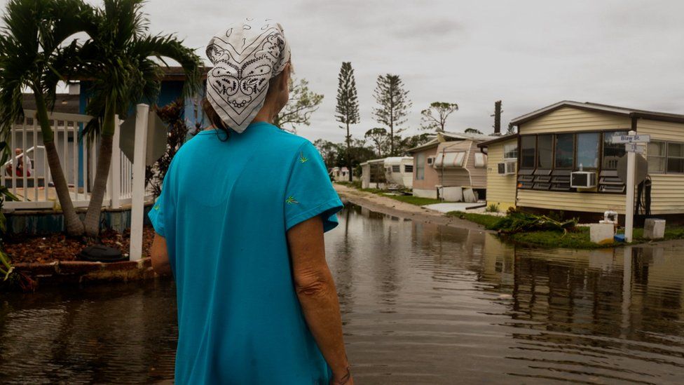 A woman looks at a flooded mobile home park near Fort Myers, Florida