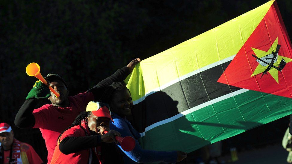 Fans blow vuvuzela horns next the Mozambique flag in front Wanderes Stadium in Johannesburg on June 8, 2010 before a friendly match between Portugal and Mozambique ahead of the start of the 2010 World Cup football tournament on June 11 in South Africa