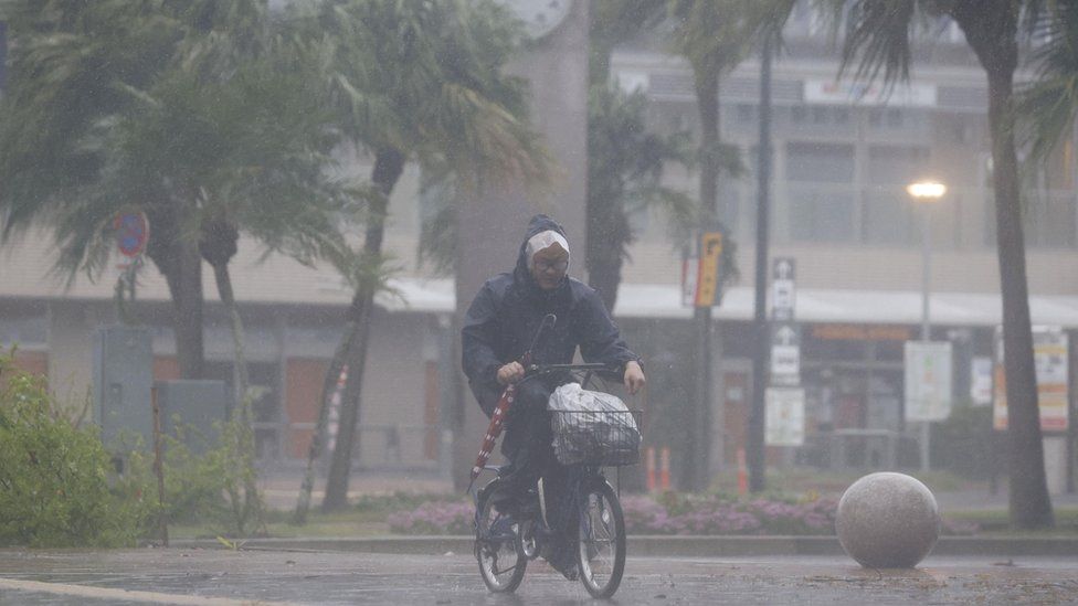 A man cycles through torrential and winds in the city of Miyazaki after Typhoon Nanmadol made landfall in Japan