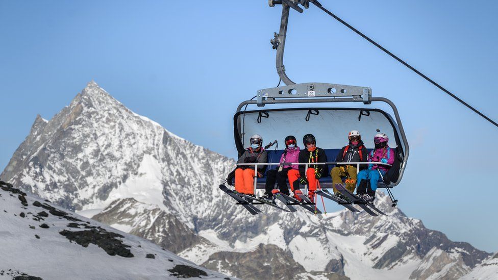 Skiers, some with face masks against the spread of Covid-19, ride a ski lift above Zermatt in the Swiss Alps, 28 Nov 20
