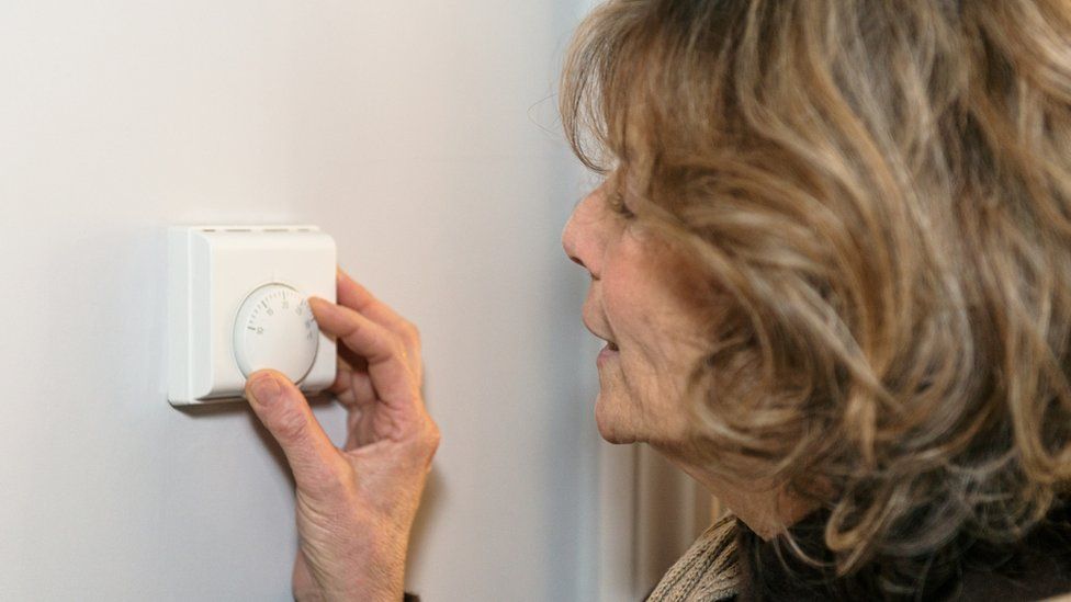 woman adjusts thermostat