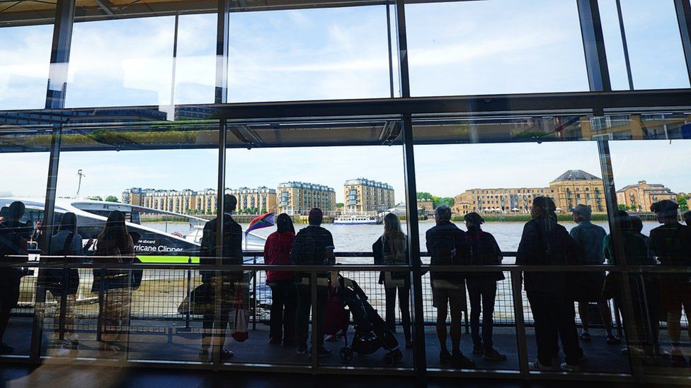 Passengers wait for the Thames Clippers Uber Boat service at Canary Wharf, London