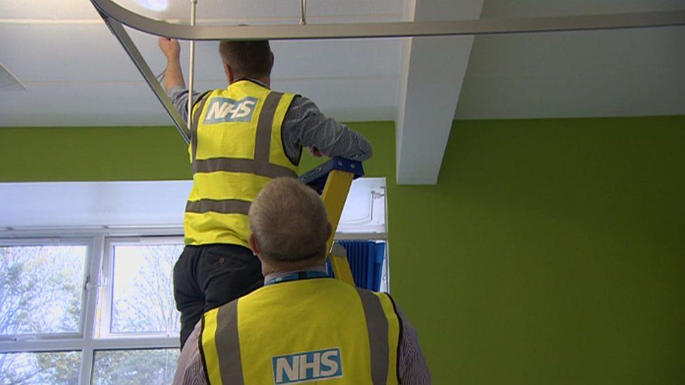 Работники NHS смотрят на крышу больницы