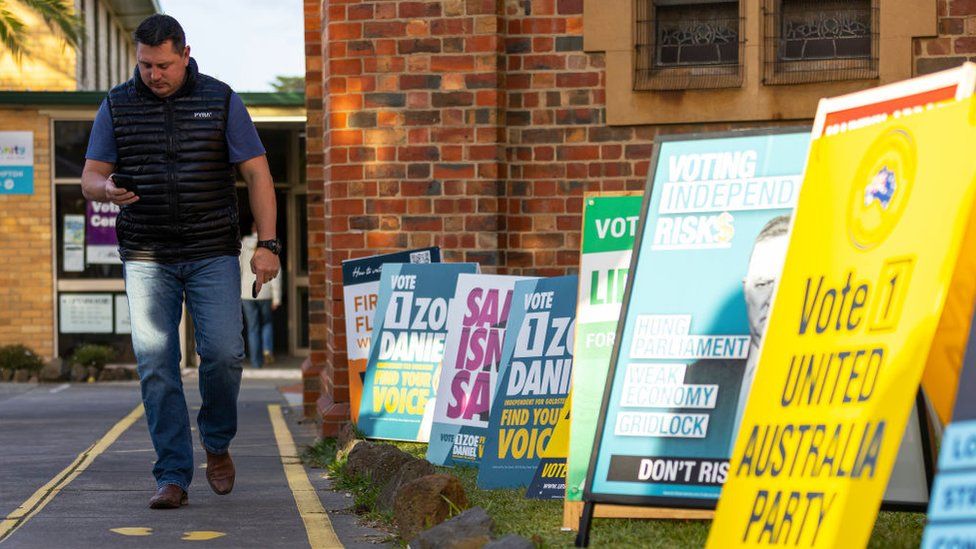 A man walks past a row of signs advertising candidates running in the Australian election