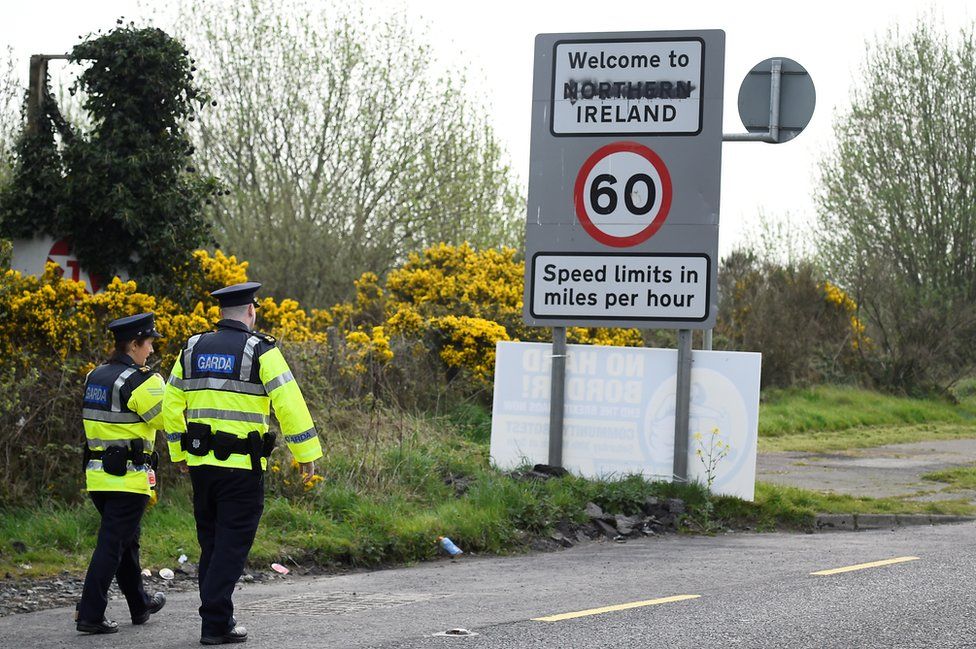 Irish police officers walk on a road that crosses the border between the Republic of Ireland and Northern Ireland